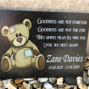 A memorial plaque with a teddy bear and quote.