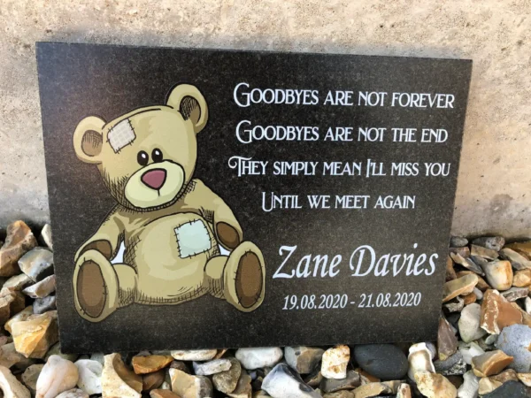 A memorial plaque with a teddy bear and quote.